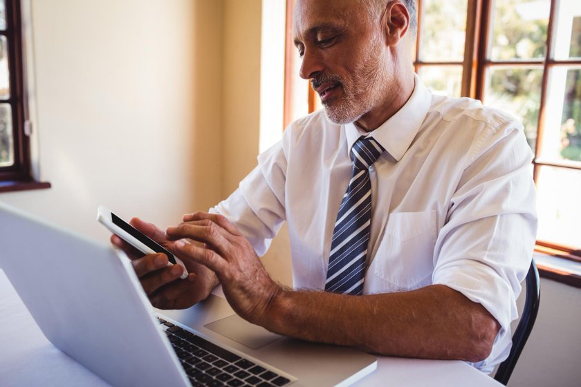 An agent comparing auto carrier quotes on a laptop and phone
